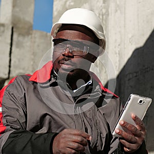 African american workman with smartphone at construction site