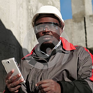 African american workman with smartphone at construction site