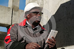 African american workman with smartphone at construction site