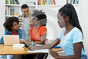 African american young adult with dreads and group of students