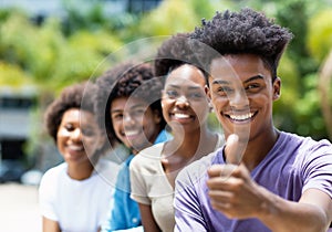 African american young adult man with friends showing thumb up