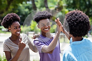 African american young adults give high five to friend with afro hair photo