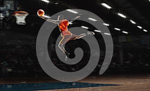 African-american young basketball player in action and flashlights over gym background. Concept of sport, movement