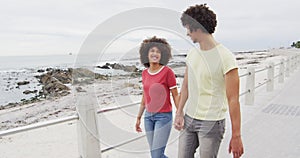 African american young couple holding hands walking together on the promenade