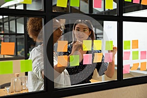 African american young female scrum master working with vietnamese colleague.