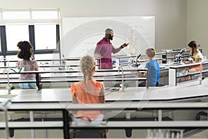 African american young male teacher explaining skeleton to multiracial students in laboratory