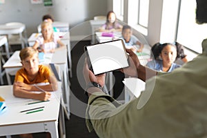 African american young male teacher holding digital tablet while teaching multiracial students