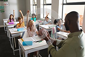 African american young male teacher showing brain model to multiracial students with hand raised