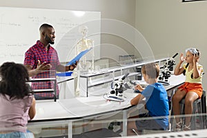 African american young male teacher teaching to multiracial elementary students in laboratory