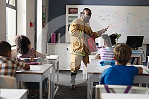 African american young male teacher in uniform teaching fire extinguisher to multiracial students