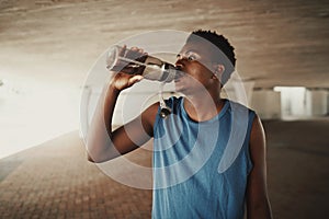 African american young man drinking water from bottle after jogging at outdoors