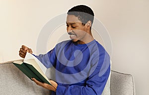 African American young man engrossed in literature, reading book indoor