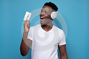 African american young man in headphones holding an old music tape.