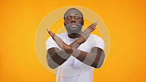 African american young man showing stop sign with hands, on yellow background