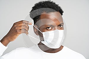 African American young man wearing face medical mask, looking at camera, isolated on grey background. Protection against flu,
