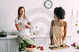 african american young woman cutting eggplant and talking to boyfriend