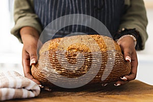 African American young woman holding freshly baked bread at home with copy space