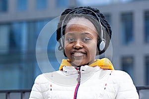 African american young woman listening music on wireless headphones outdoor