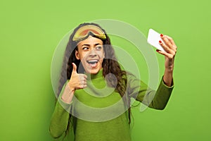 African-american young woman`s portrait in ski mask on green background