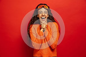 African-american young woman`s portrait in ski mask on red background