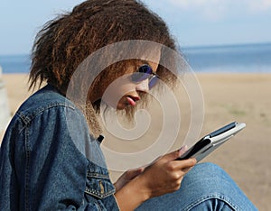 African american young woman with tablet on the beach