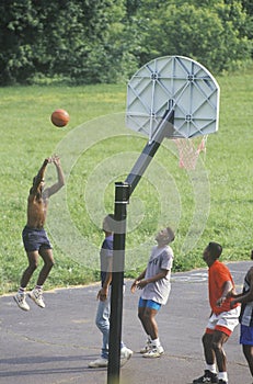 African-American youths playing street basketball,