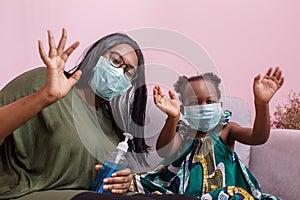 African Americans` mother and daughter wearing a mask are washing their hands with alcohol to protect them from germs and COVIC 1