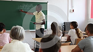 African americn male teacher explaining new theme to adult students during class in university indoors