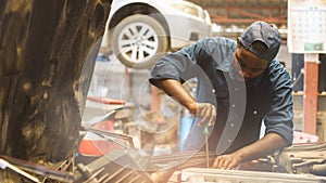 African auto mechanic inspects a car that has a problem with overheating causing smoke