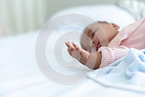 African baby newborn sleeping and lying on a white bed