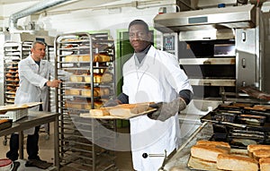 African baker carrying baked bread on tray