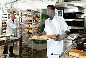 African baker carrying baked bread on tray