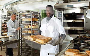 African baker carrying baked bread on tray