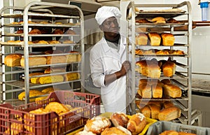 African baker carrying fresh bread on trolley