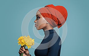 African beautiful girl in a colored headscarf on her head holding flowers in her hand