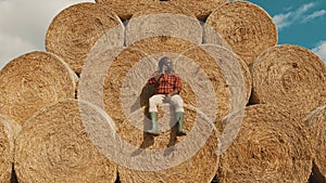 African black farmer sitting on the haystack and having a phone call