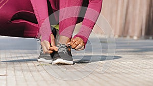 African black female finishes race stops bends over to tie shoelaces on running shoes. Woman athlete preparing for