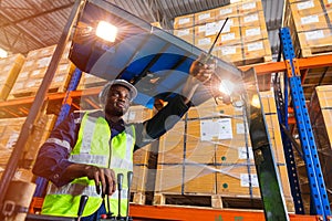 African black male staff worker working control loading operate folk lift in warehouse inventory factory