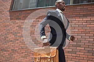 African black young businessman running in a city