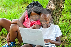 African boy and girl playing on laptop.