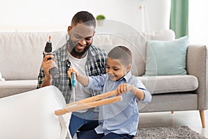African Boy Helping Father Fix Table Doing Housework At Home