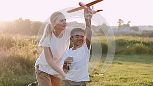 African boy and mother playing toy plane in the field