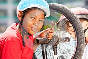 African boy repairing bicycle wheel with spanner