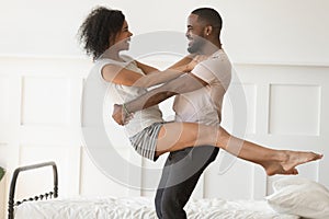 African boyfriend holds beloved girlfriend in his arms in bedroom