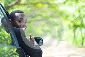 African business man driving and  smiling while sitting in a car with open front window