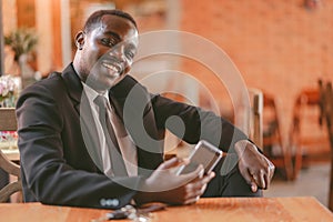 African business man using smartphone in restaurant with smile and happy