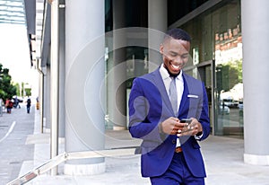 African business man walking and looking at mobile phone
