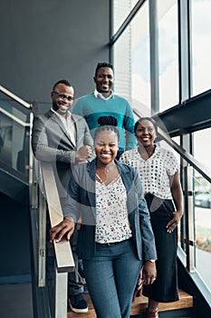 African business people smiling and standing on stairs in a modern office
