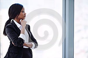 African business woman looking out window in thought about investments