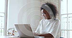 African business woman wear headphone make video call on laptop